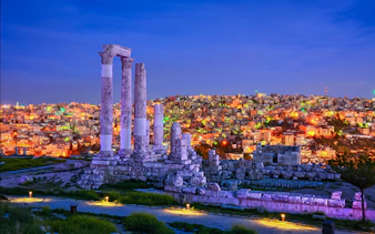 Roman Temple of Hercules ruins overlooking Amman cityscape at dusk.