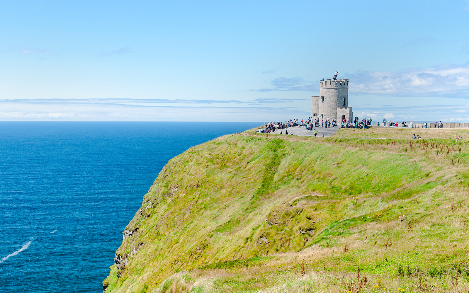 O'Brien's Tower overlooking the Cliffs of Moher, Ireland, with visitors nearby.