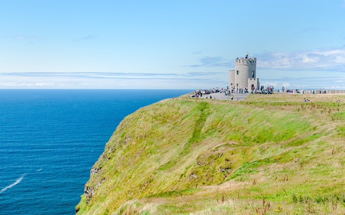 O'Brien's Tower overlooking the Cliffs of Moher, Ireland, with visitors nearby.