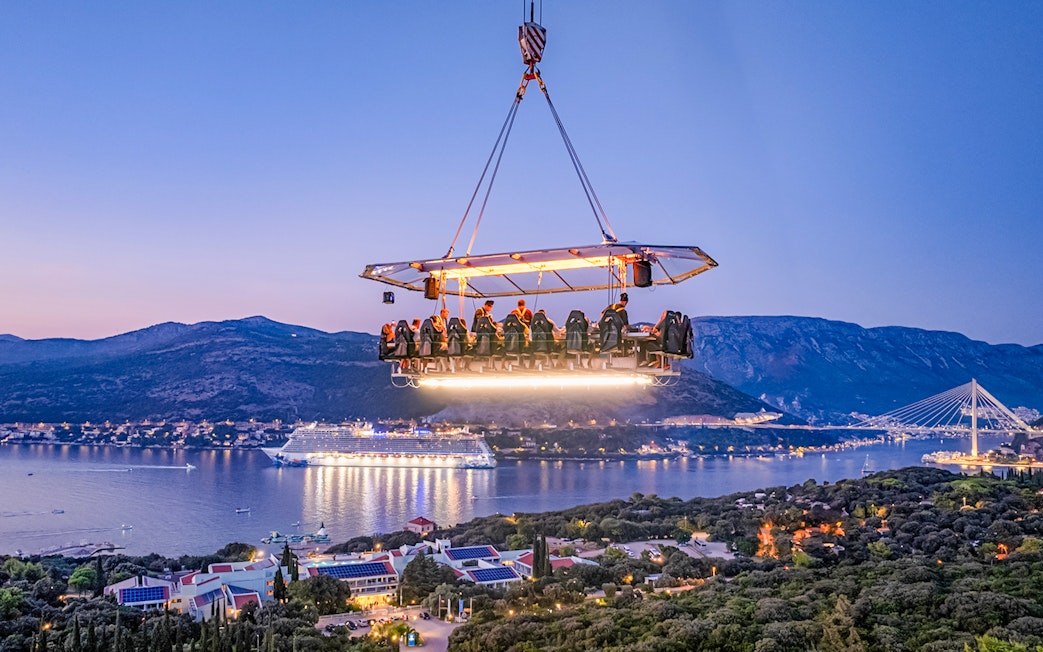 Guests dining on a suspended platform above Dubrovnik with a view of the Adriatic Sea.