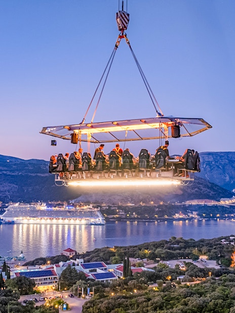 Guests dining on a suspended platform above Dubrovnik with a view of the Adriatic Sea.