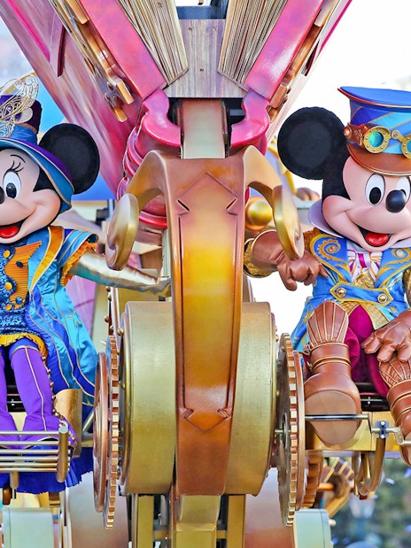 Mickey and Minnie Mouse in colorful costumes on a parade float at Disneyland Paris.