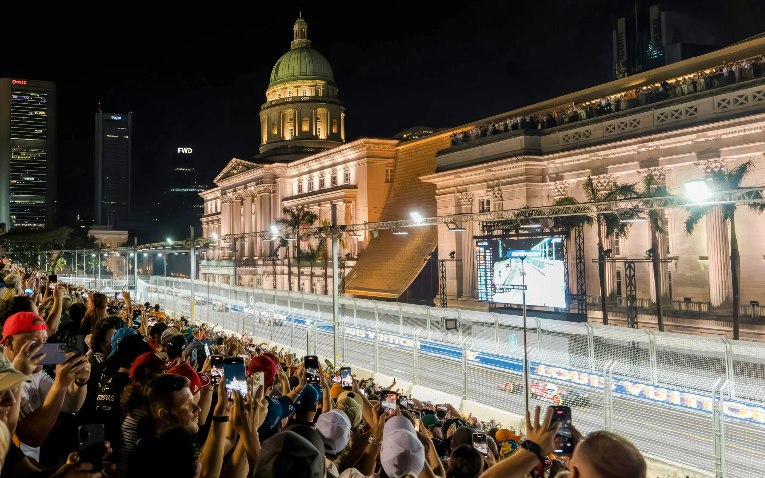 Crowd watching Formula 1 Singapore Grand Prix at Marina Bay Street Circuit with National Gallery Singapore in view.