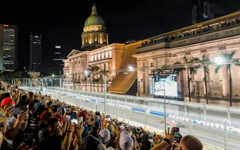 Crowd watching Formula 1 Singapore Grand Prix at Marina Bay Street Circuit with National Gallery Singapore in view.