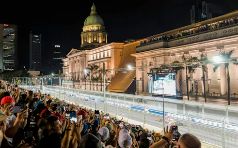 Crowd watching Formula 1 Singapore Grand Prix at Marina Bay Street Circuit with National Gallery Singapore in view.