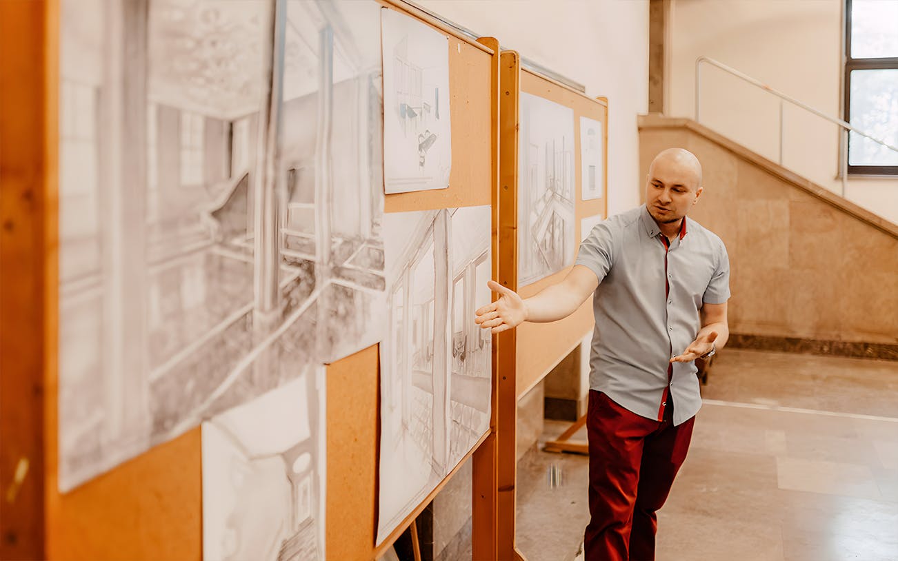 Tour guide explaining architectural drawings at Nowa Huta Steelworks, Kraków.
