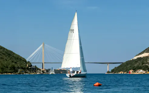 Yacht sailing near Dubrovnik with Franjo Tuđman Bridge in the background.