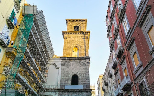San Lorenzo Maggiore bell tower in Naples, Italy, surrounded by historic buildings.