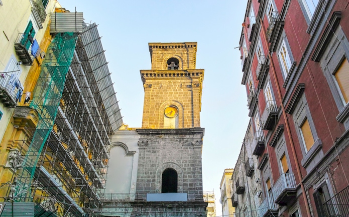 San Lorenzo Maggiore bell tower in Naples, Italy, surrounded by historic buildings.