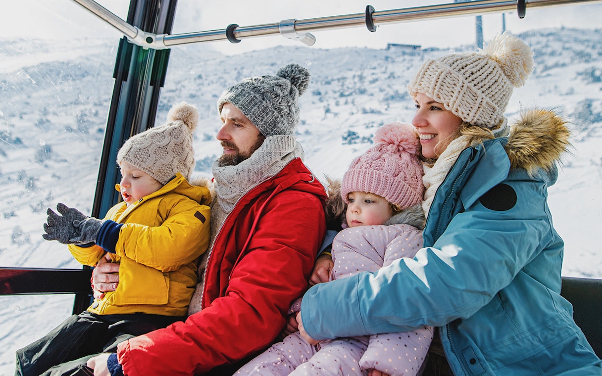 Family enjoying snowy mountain views from a cable car.