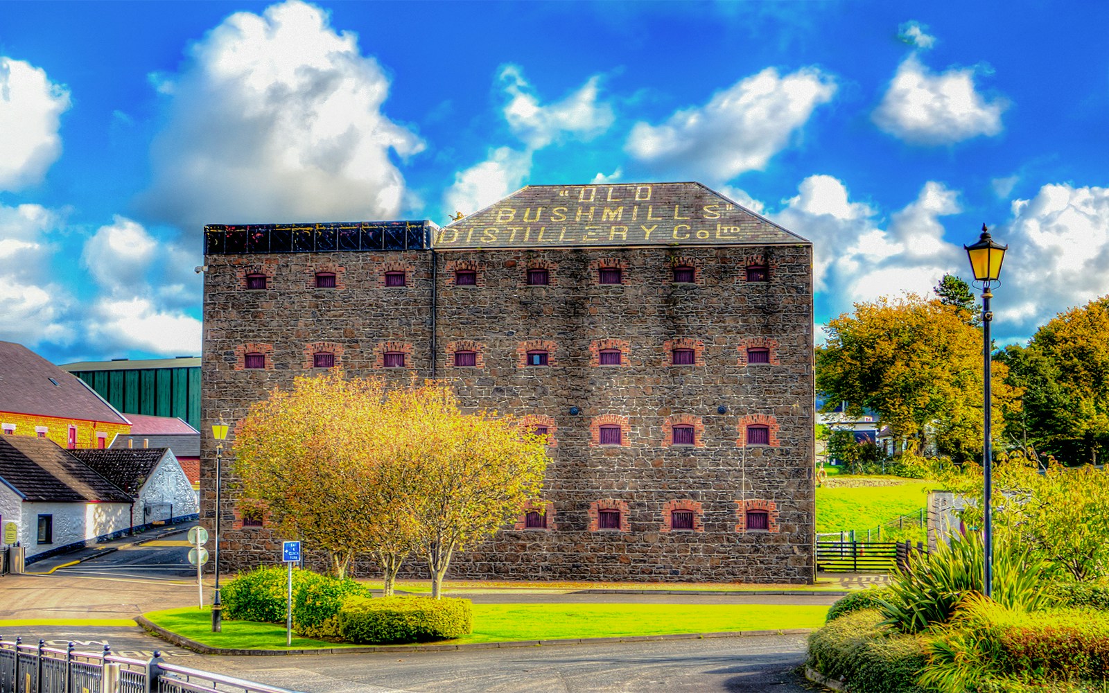 Old Bushmills Distillery building with stone facade and surrounding greenery in Northern Ireland.