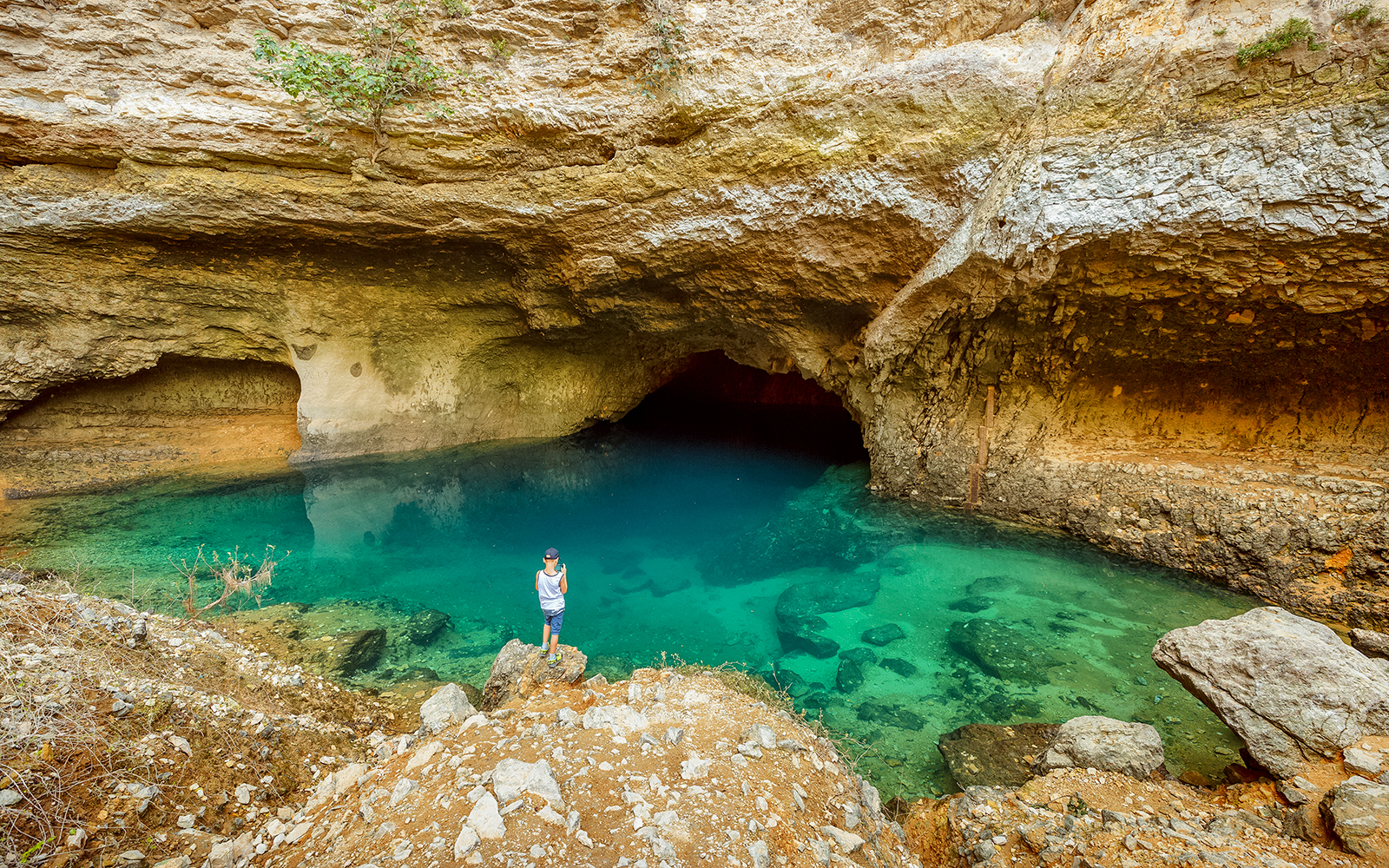 Cave with turquoise water and rocky surroundings in Provence, part of a guided tour from Avignon.