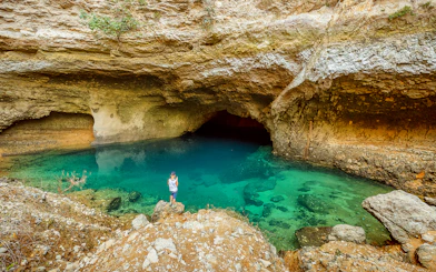 Cave with turquoise water and rocky surroundings in Provence, part of a guided tour from Avignon.