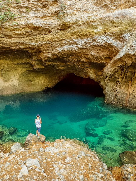 Cave with turquoise water and rocky surroundings in Provence, part of a guided tour from Avignon.