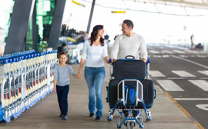 Family with luggage at Haneda Airport for airport transfer.