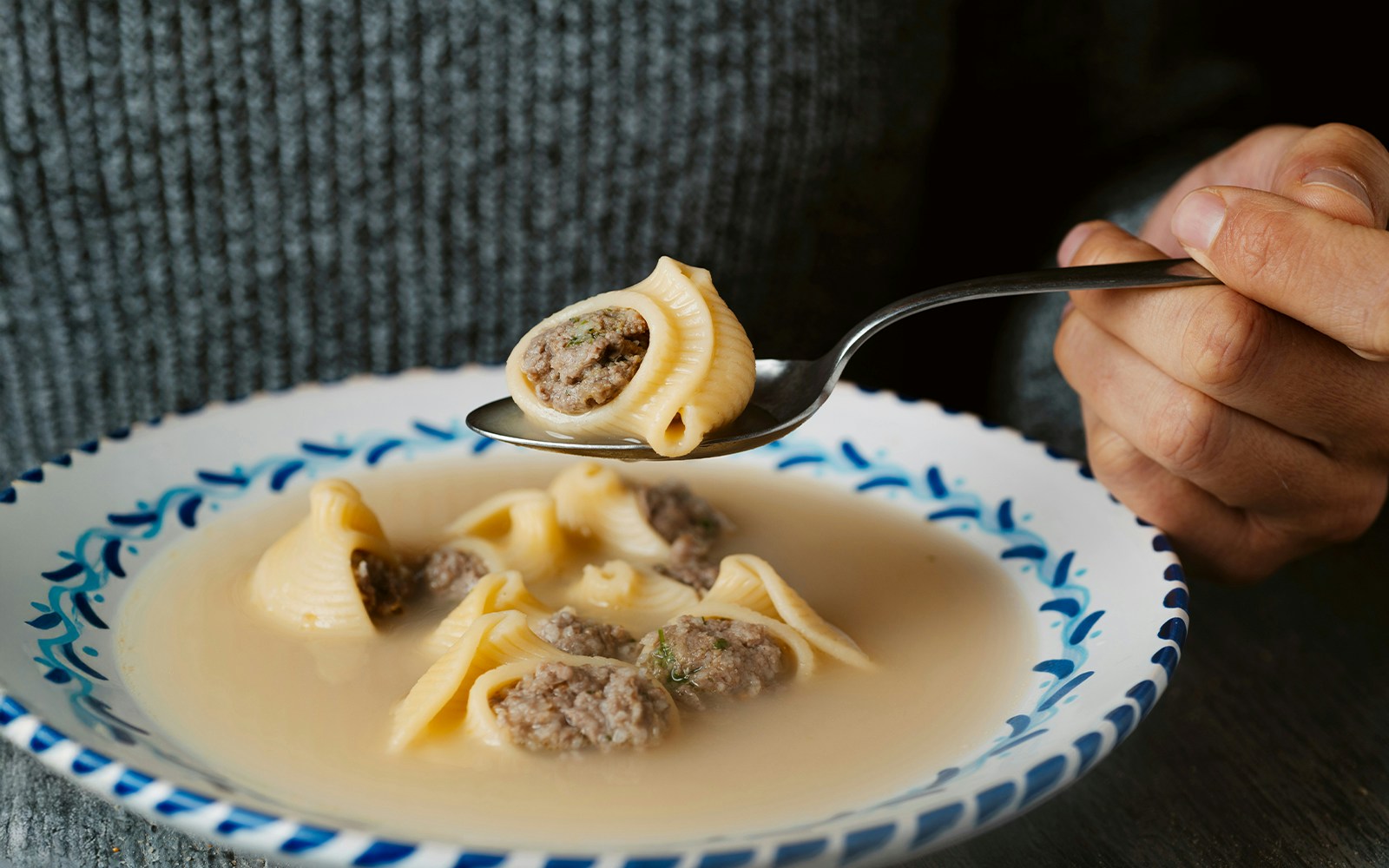 Man holding spoon with Catalan escudella de Nadal soup.