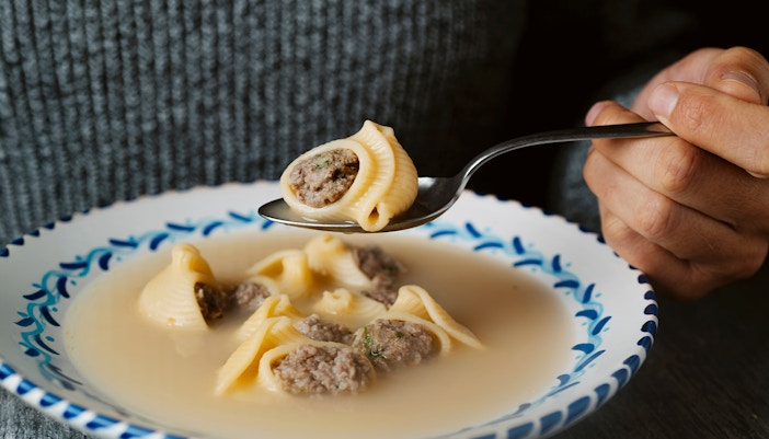 Man holding spoon with Catalan escudella de Nadal soup.