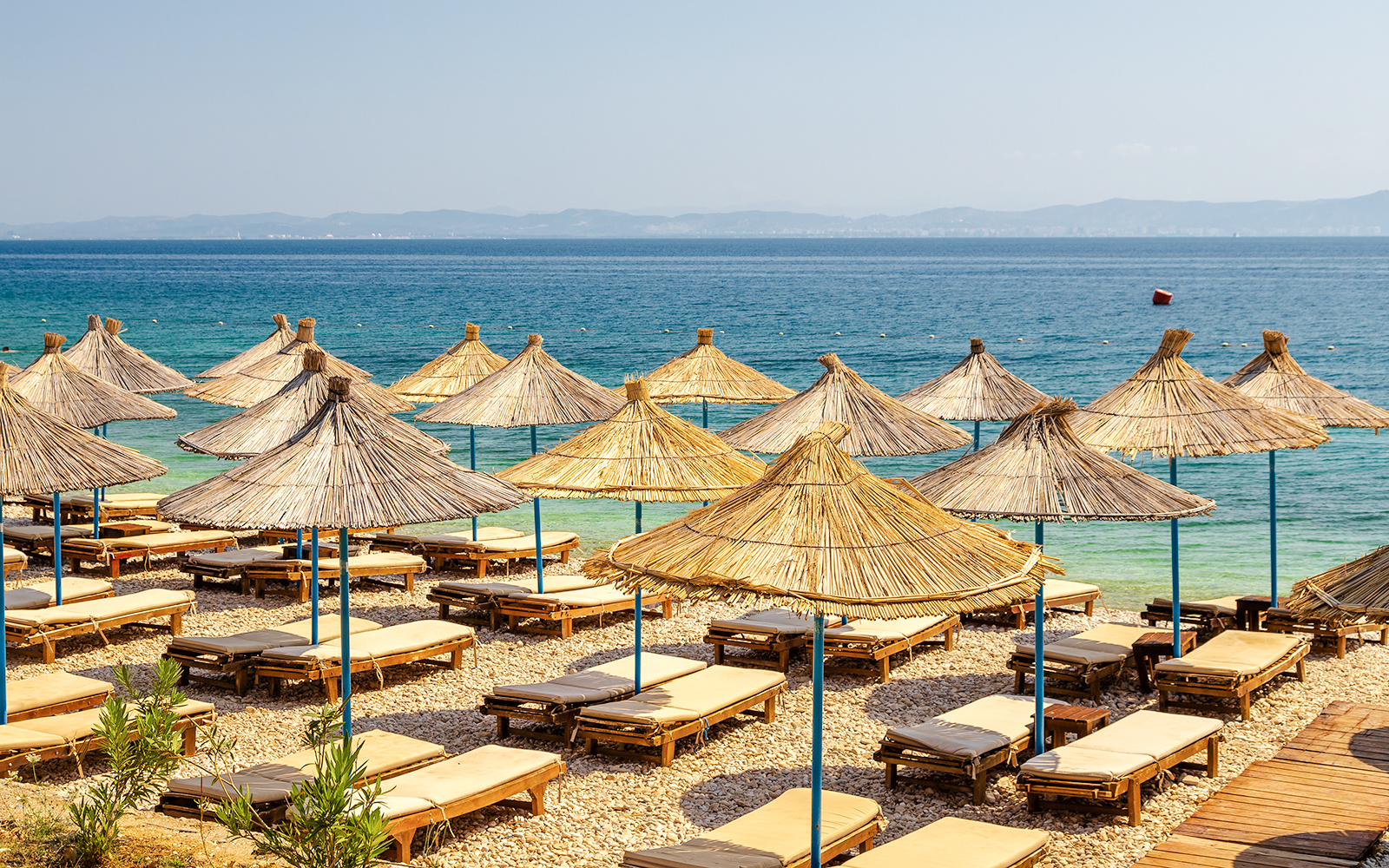 Sun loungers and straw umbrellas on Karaburun Peninsula beach, Albania.