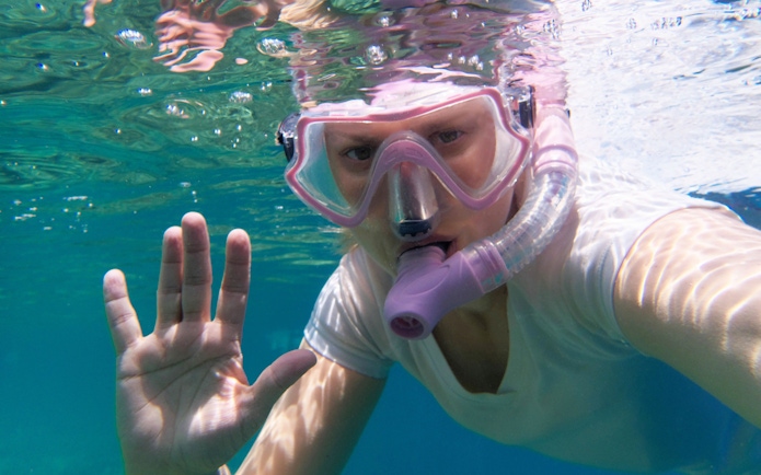 Snorkeler underwater at Giftun Island, Hurghada, waving to the camera.