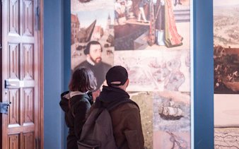 Visitors viewing historical paintings inside Bruges City Hall.