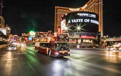 Big Bus tour driving on Las Vegas Strip at night near Treasure Island.