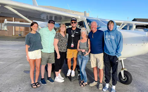 Group posing by small aircraft before Private Kauai Air Tour.