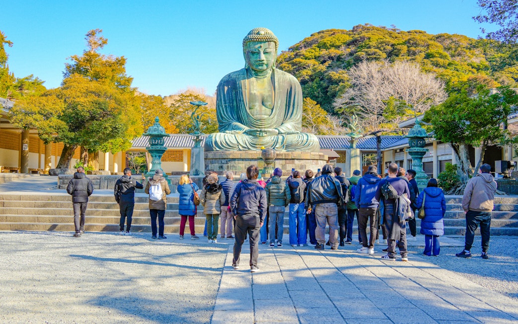 Tourists viewing the Great Buddha statue in Kamakura during a guided tour.