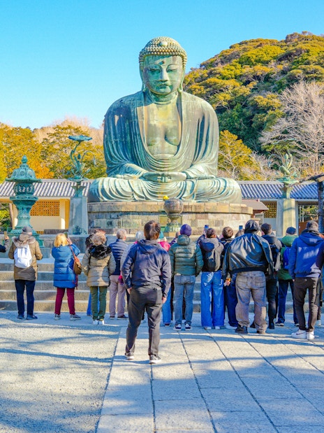 Tourists viewing the Great Buddha statue in Kamakura during a guided tour.