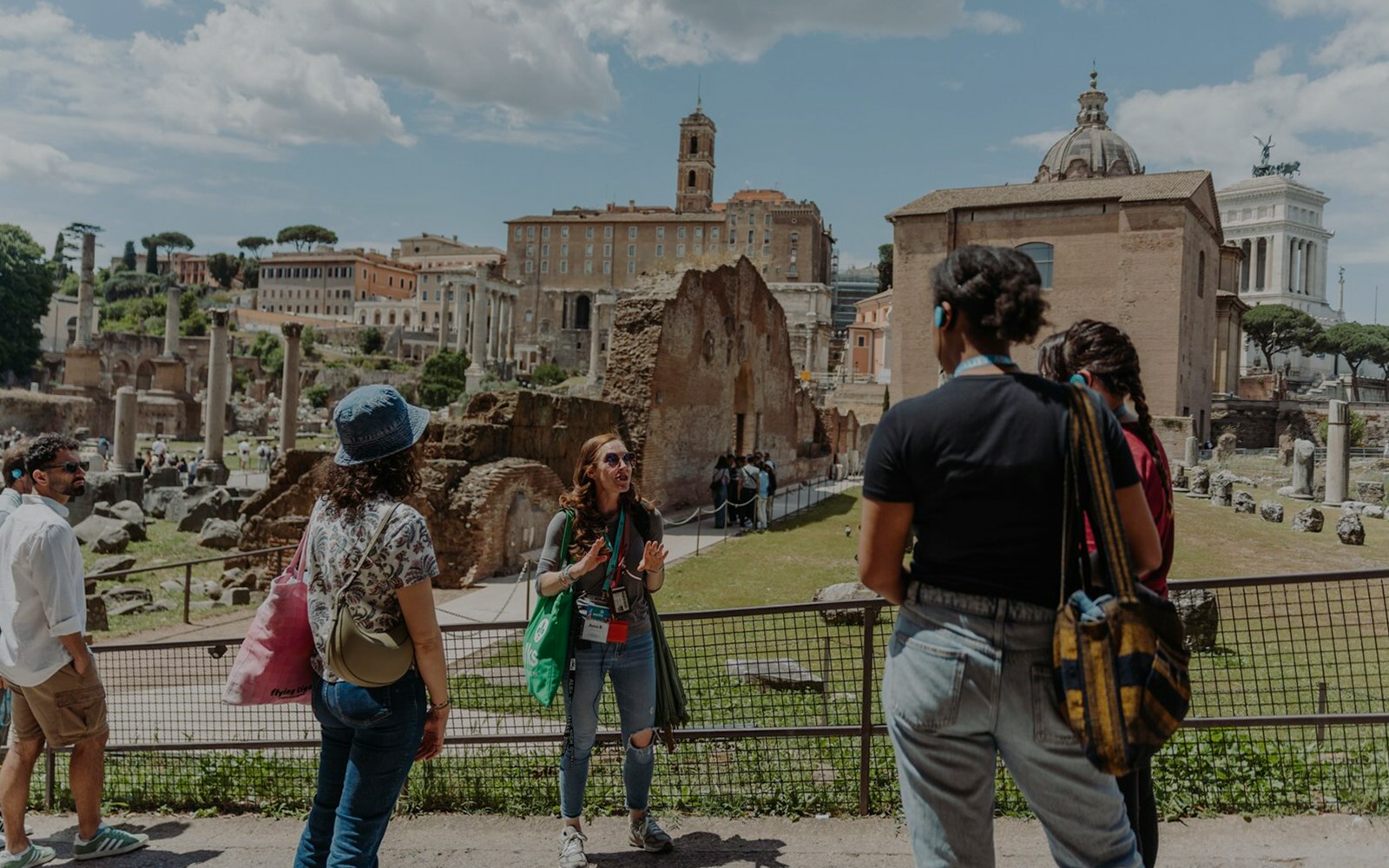 Tour guide with group at Palatine Hill, Rome, with ancient ruins in the background.