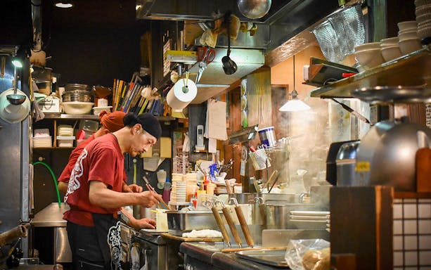 Chef preparing ramen in a bustling Tokyo kitchen during the Ultimate Ramen Tasting Tour.