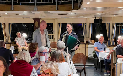 Accordion player performing for guests on Budapest Danube River dinner cruise.