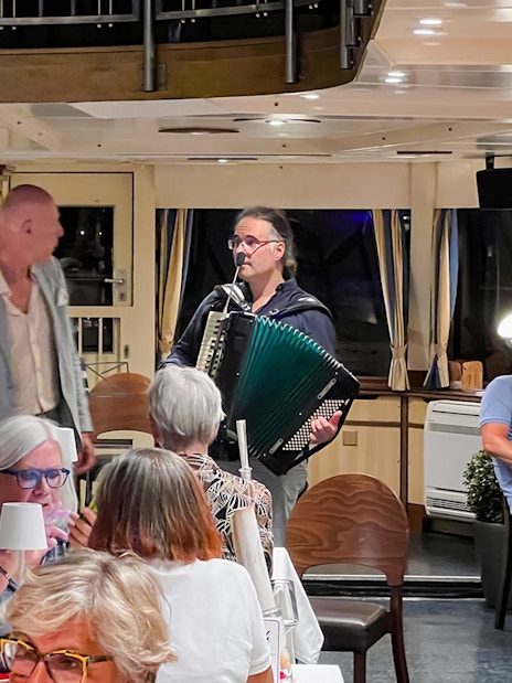 Accordion player performing for guests on Budapest Danube River dinner cruise.