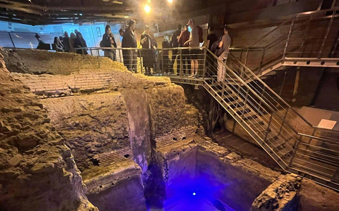 Visitors exploring ancient ruins on the Trevi District Underground guided tour in Rome.