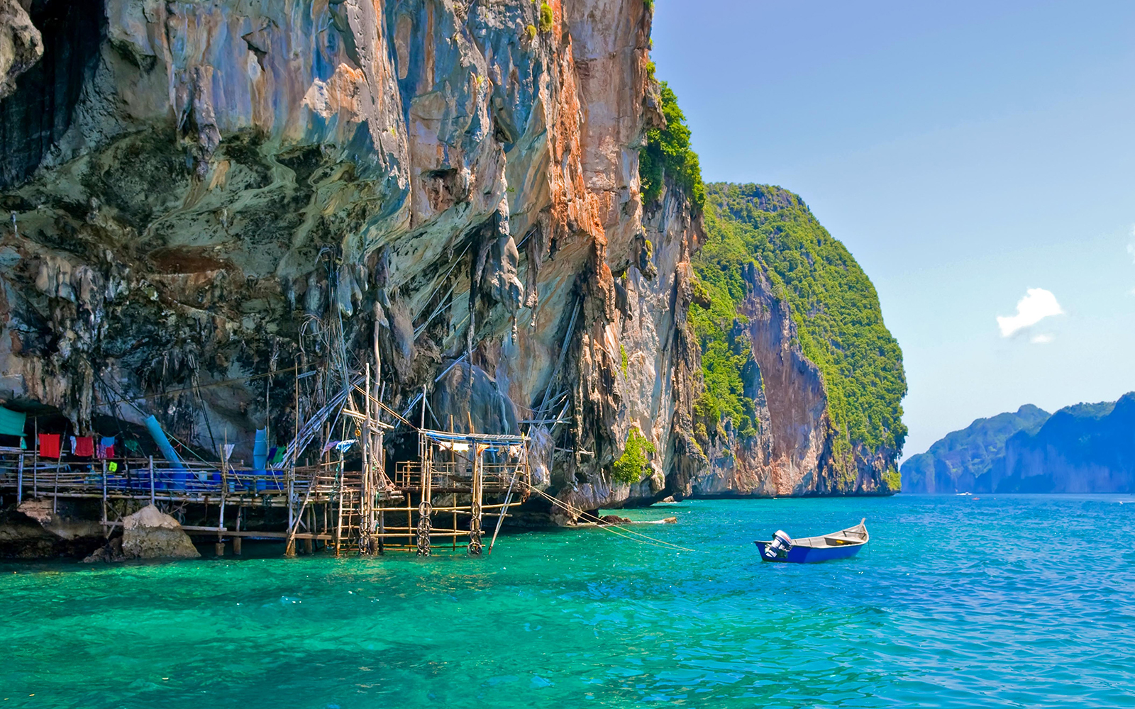 Viking Cave with wooden scaffolding and boat in turquoise waters, Ko Phi Phi, Thailand.