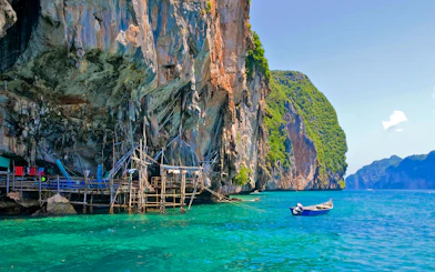 Viking Cave with wooden scaffolding and boat in turquoise waters, Ko Phi Phi, Thailand.