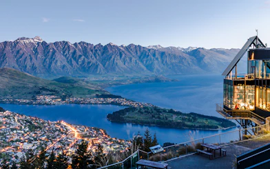 Aerial view of Queenstown with Lake Wakatipu and surrounding mountains at sunset.