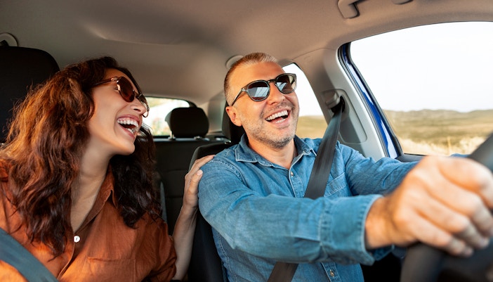 Couple smiling while driving on a road trip from Rome to Naples.
