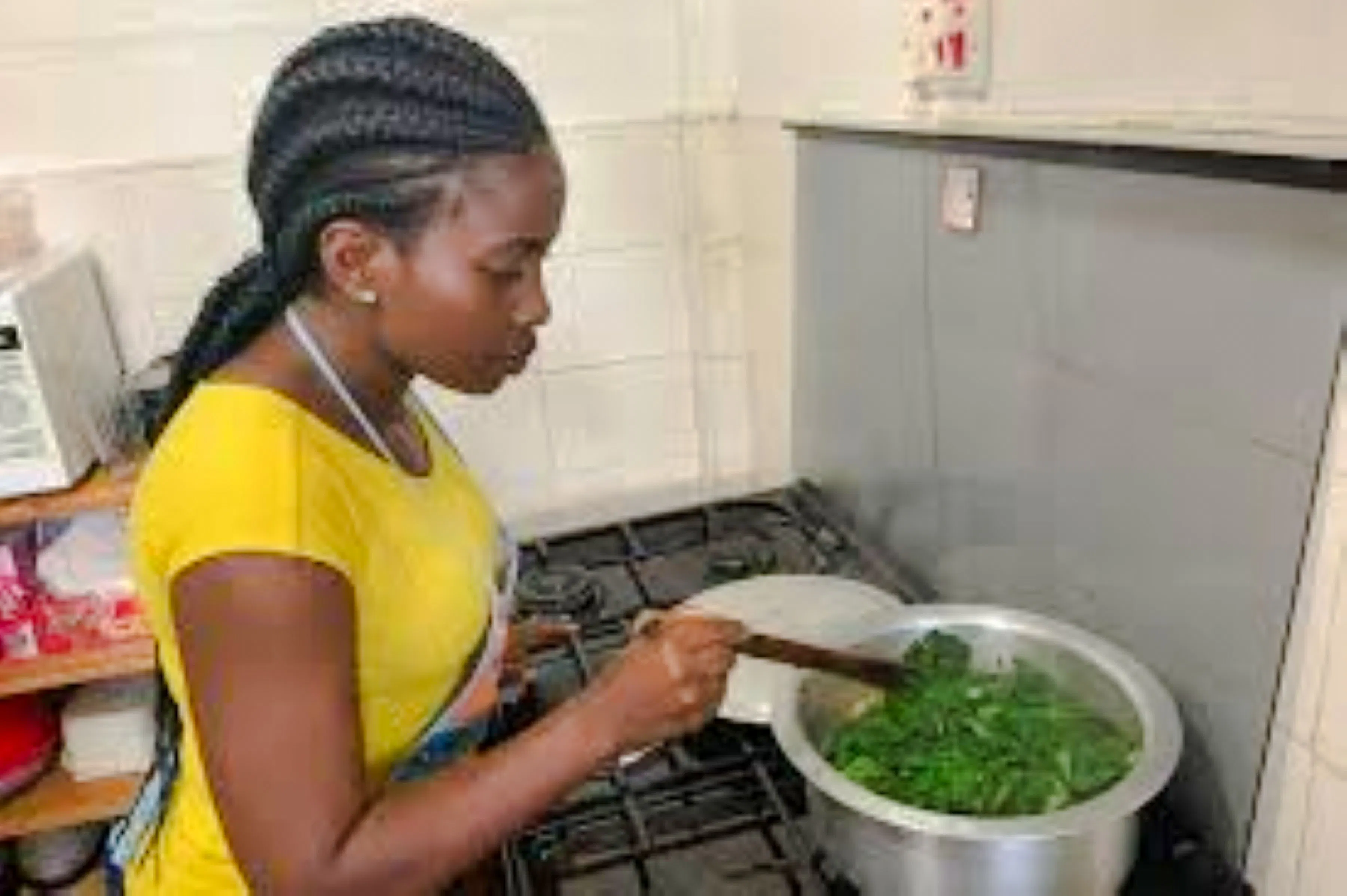 Woman cooking traditional dish in Nairobi kitchen during market visit and cooking class.