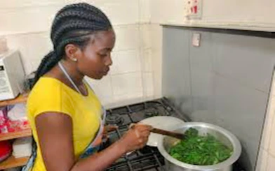 Woman cooking traditional dish in Nairobi kitchen during market visit and cooking class.