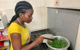 Woman cooking traditional dish in Nairobi kitchen during market visit and cooking class.