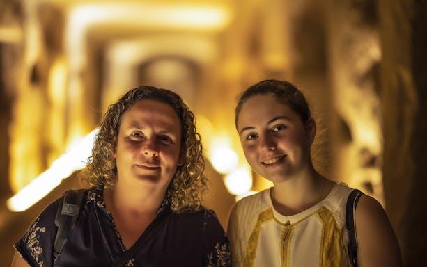 Visitors exploring the illuminated corridors of the Roman Catacombs.