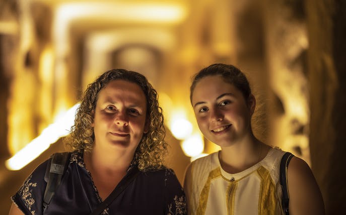 Visitors exploring the illuminated corridors of the Roman Catacombs.