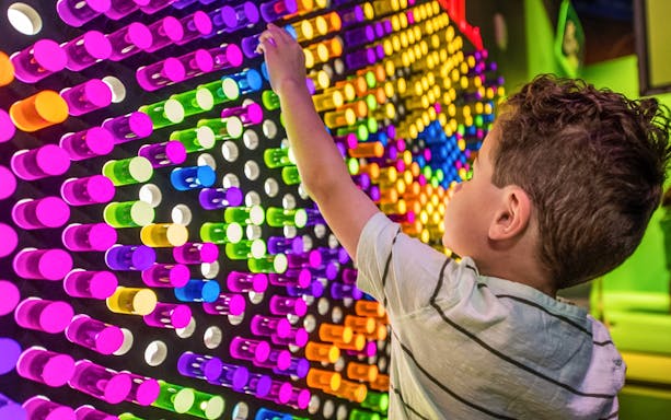 Child interacting with colorful light display at San Antonio attraction.