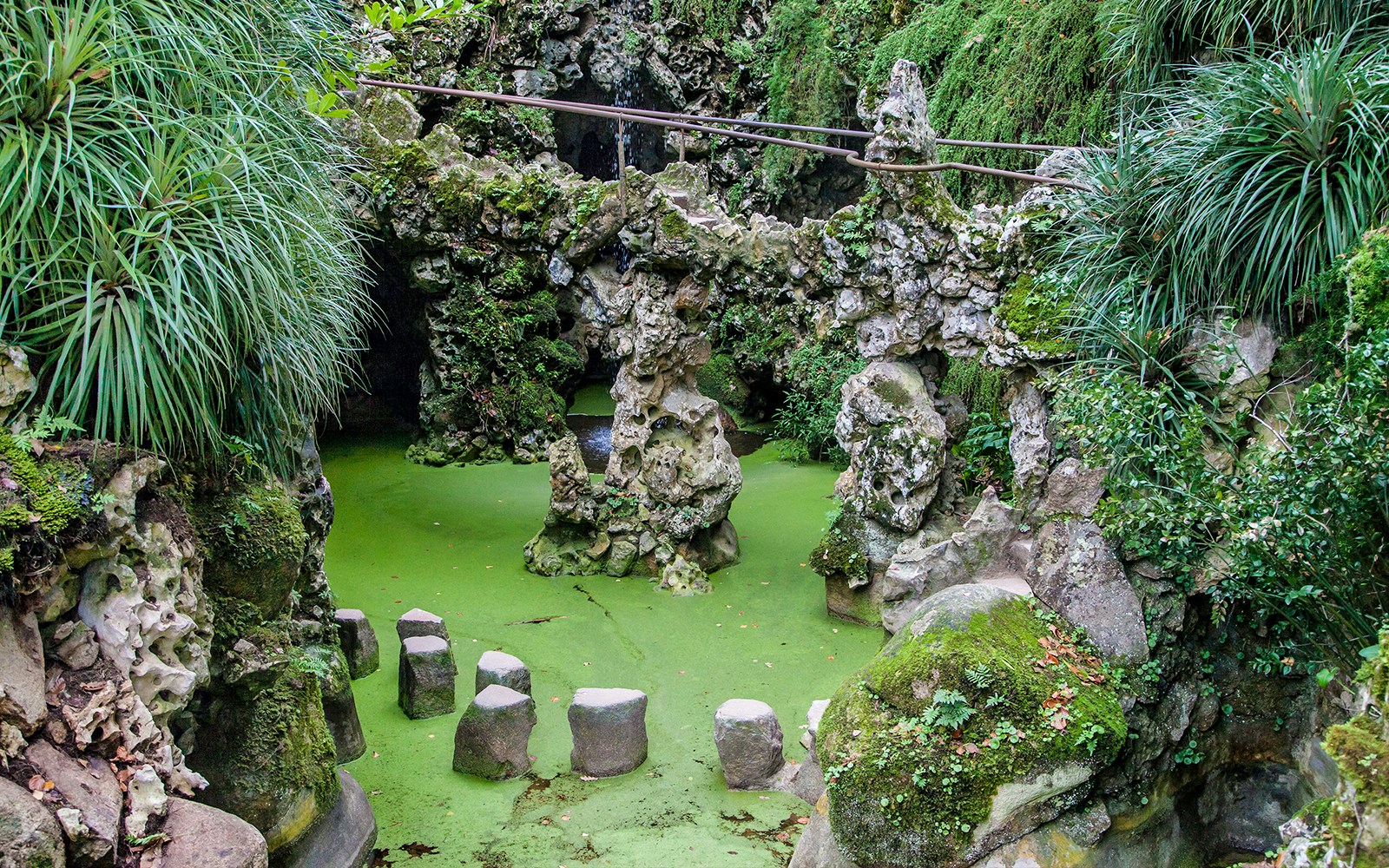 Stepping stones over green water at Waterfall Lake, Quinta da Regaleira, Sintra, Portugal.