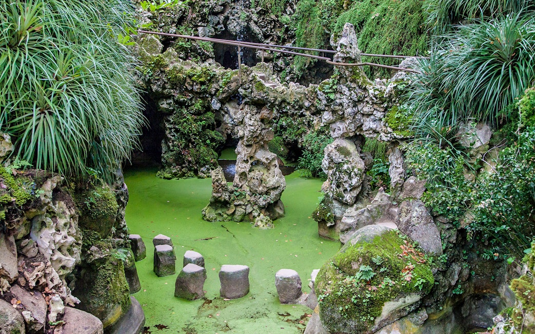 Stepping stones over green water at Waterfall Lake, Quinta da Regaleira, Sintra, Portugal.