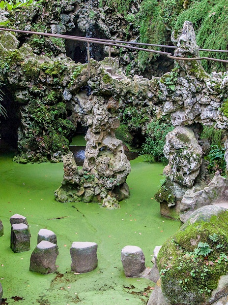 Stepping stones over green water at Waterfall Lake, Quinta da Regaleira, Sintra, Portugal.