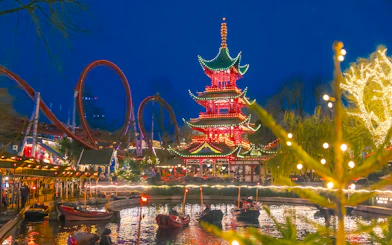 Tivoli Gardens Copenhagen at Christmas with illuminated pagoda and roller coaster.