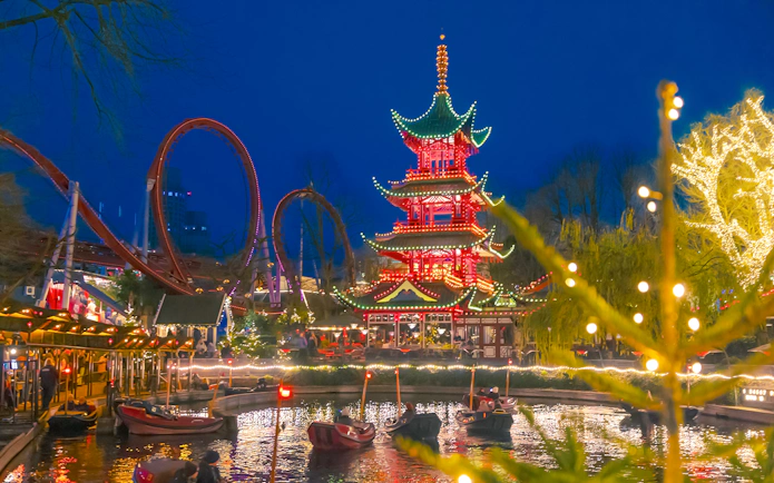 Tivoli Gardens Copenhagen at Christmas with illuminated pagoda and roller coaster.