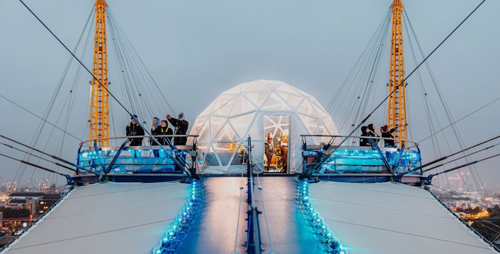 Visitors at the O2 dome summit with illuminated snow globe, London.
