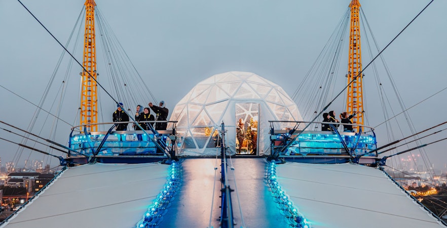 Visitors at the O2 dome summit with illuminated snow globe, London.